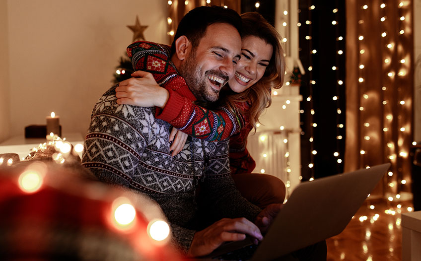 Kobieta przytula mężczyznę, wspólnie robią zakupy świąteczne w sklepie online 