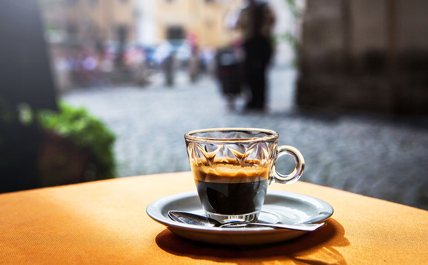 Filiżanka z kawą na stole w centrum miasta Szklana filiżanka gorącego espresso na stoliku kawiarnianym na zewnątrz