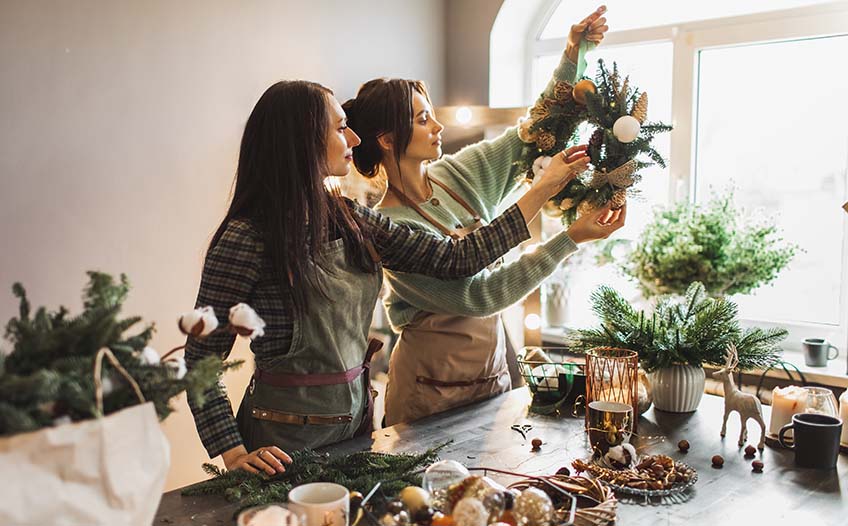 Dwie kobiety przygotowują samodzielnie świąteczny wianek 