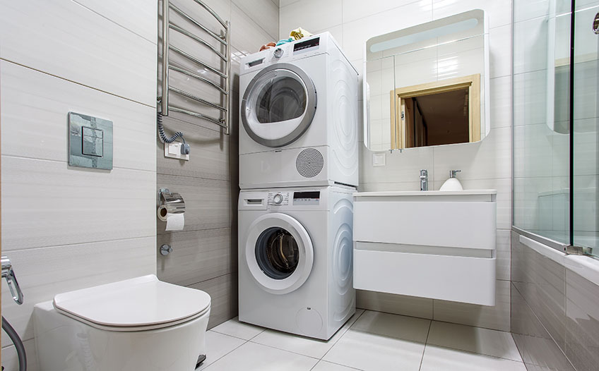 Kącik do prania w małej łazience: pralka, suszarka i pojemniki na pranie