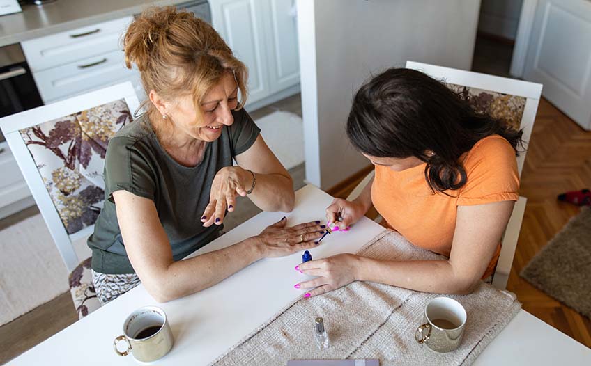 Matka i córka wspólnie robią manicure w domu przy stole