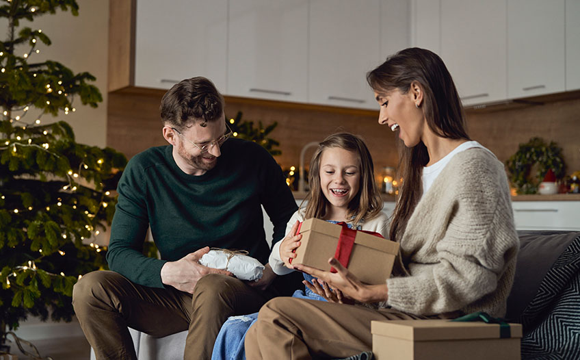 Rodzina na kanapie otwiera świąteczne prezenty