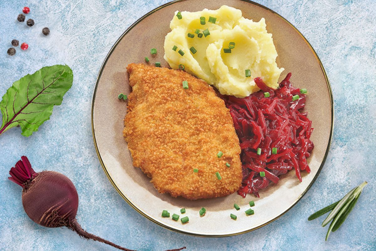 Kotlet schabowy z ziemniakami i buraczkami – klasyczny polski obiad Talerz z panierowanym kotletem, puree ziemniaczanym i buraczkami, podany na jasnym tle z dekoracją z buraka i przypraw.