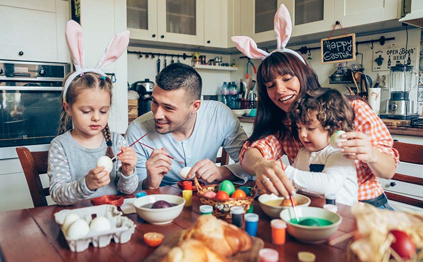 Rodzina w kuchni maluje wspólnie jajka na Wielkanoc