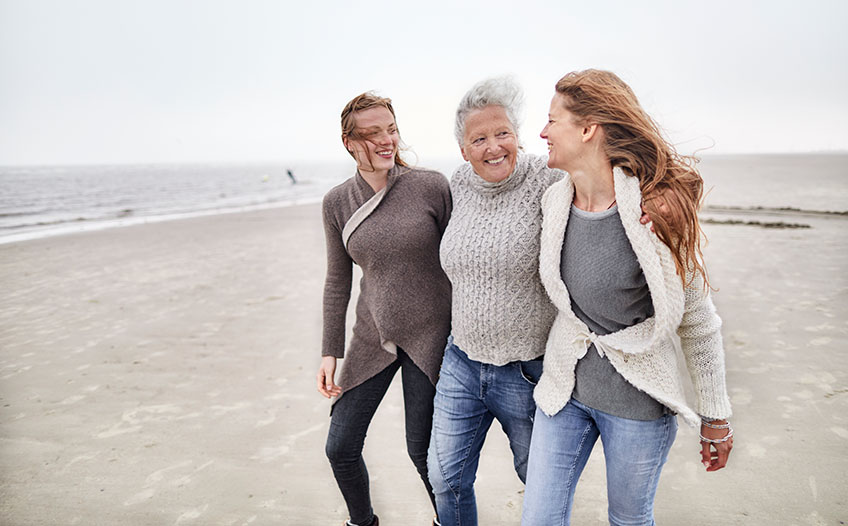 Trzy pokolenia kobiet spacerują po plaży