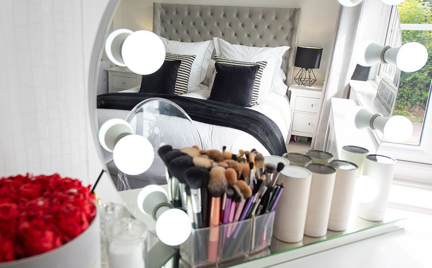 Toaletka z dużym lustrem i akcesoriami do makijażu stojąca w sypialni